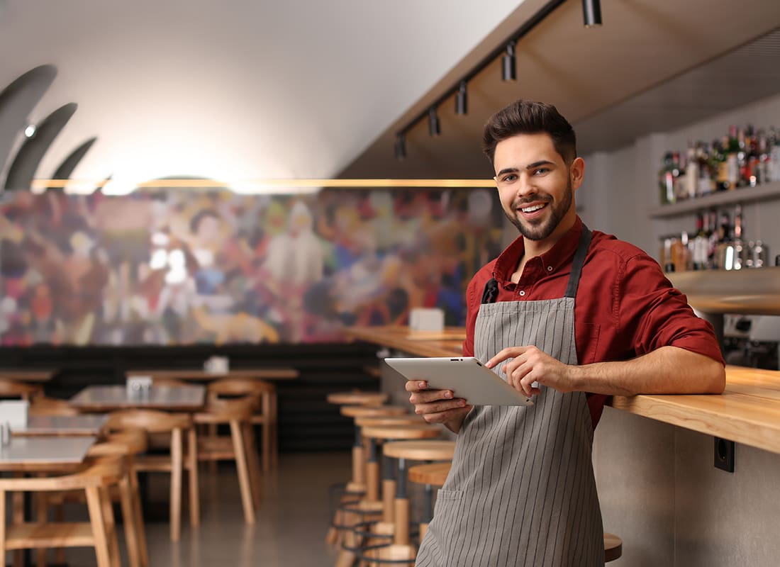Business Insurance - Young Male Business Owner With Tablet Near Counter in His Cafe